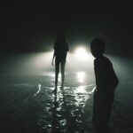 silhouettes of two people standing on the background of car lights at night